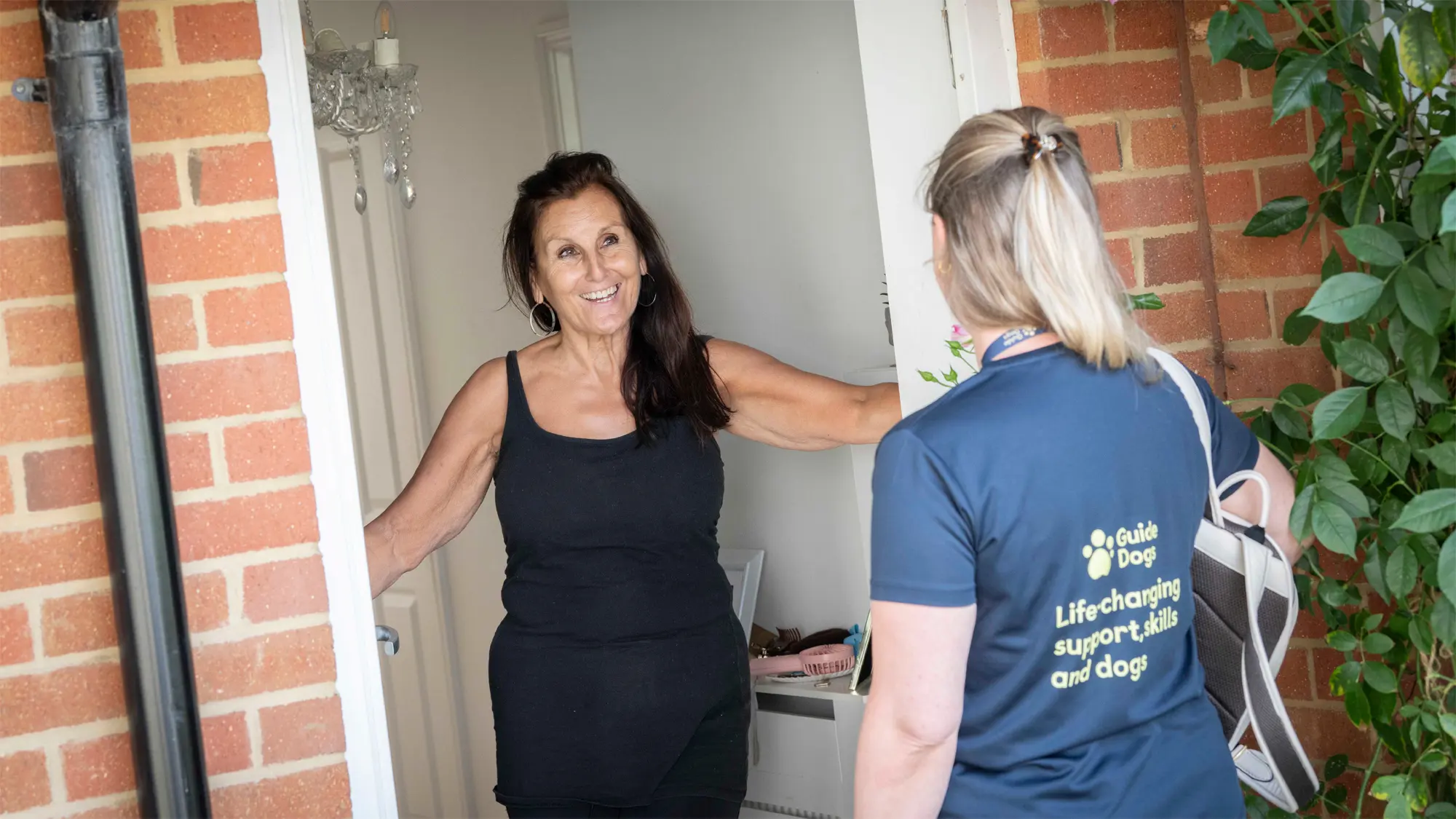 Jennie, who has a vision impairment, greets Guide Dogs Vision Rehabilitation Specialist Kealy at her front door.