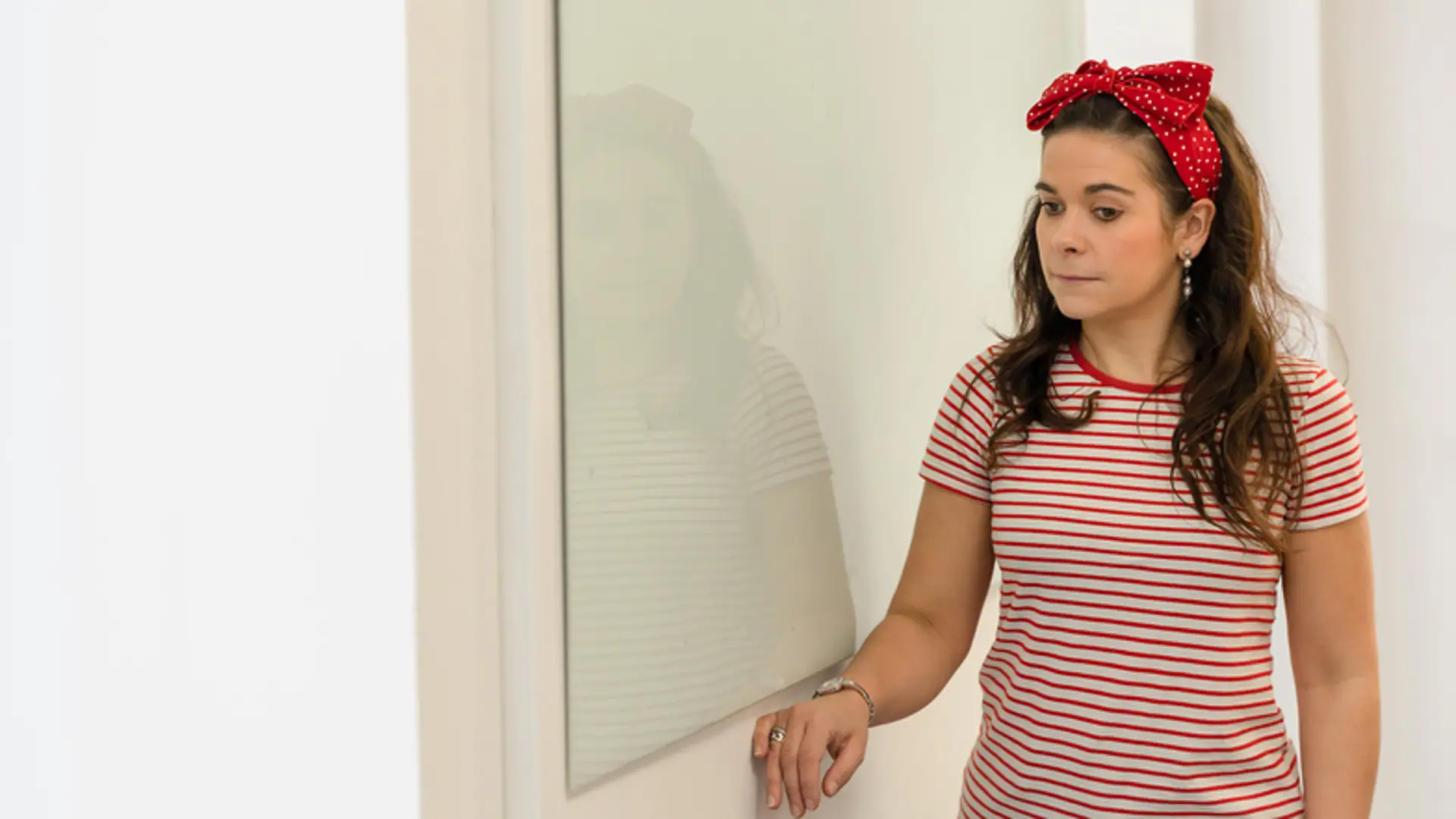 A woman runs her hand along the wall of a room, using the trailing technique to find her way.