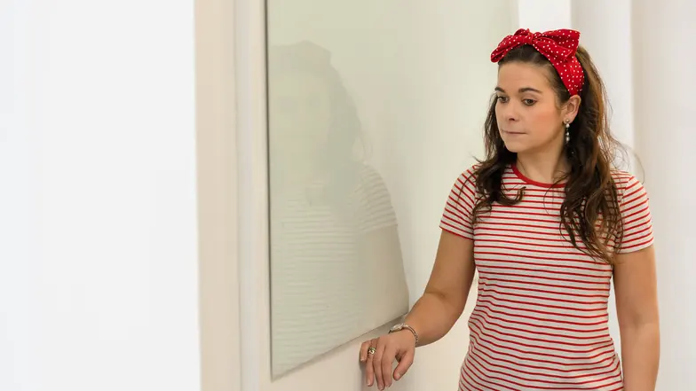 A woman runs her hand along the wall of a room, using the trailing technique to find her way.