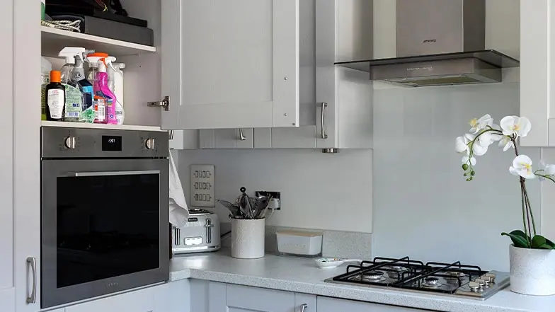 A kitchen with cleaning products stored in a high cupboard.