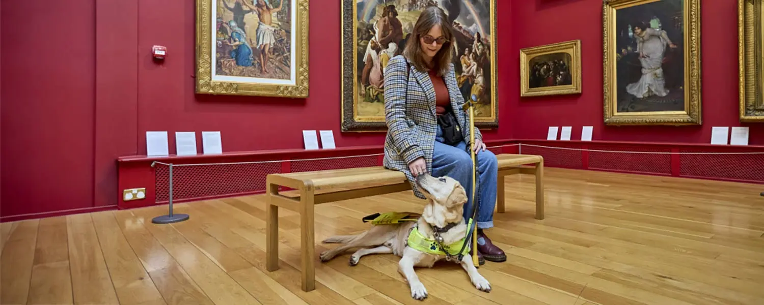 Guide Dog owner Chloe is at an art gallery with guide dog Dezzie.