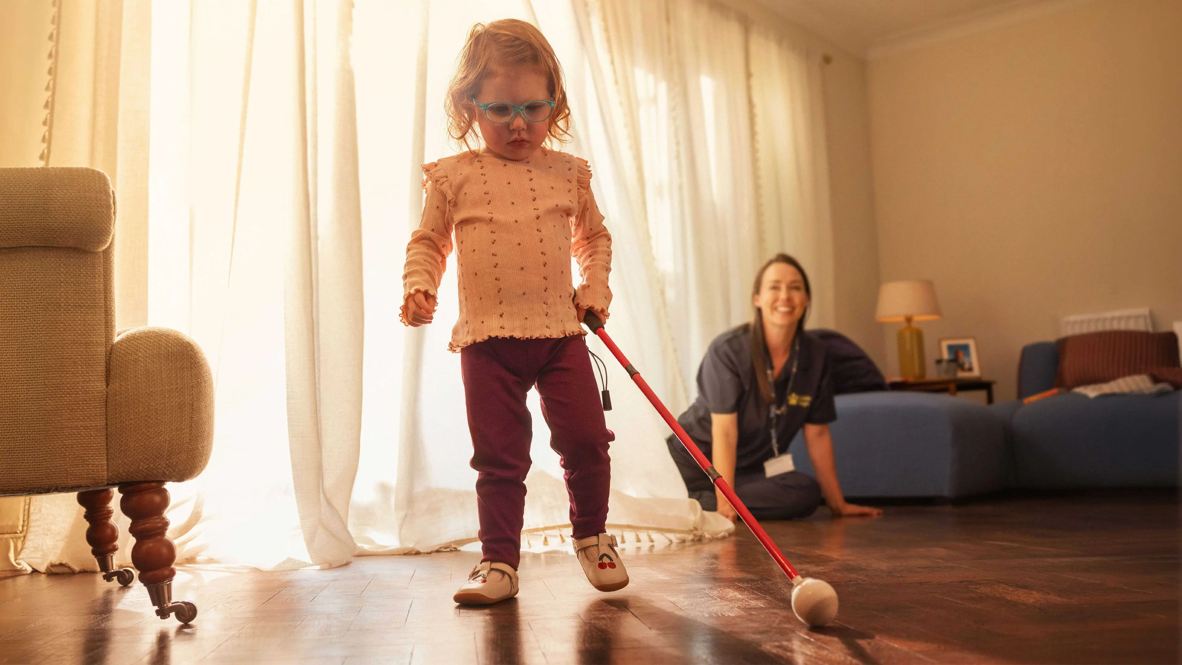 Martha - a Children and Young People's service user - takes her first steps using her long cane at home, supported by her Habilitation Specialist, Lisa.