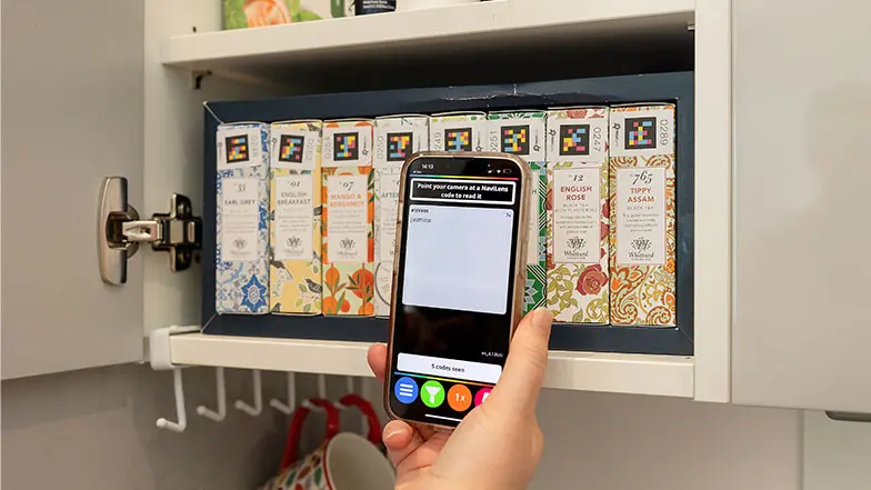 An individual using Navilens to scan different boxes of tea in their kitchen