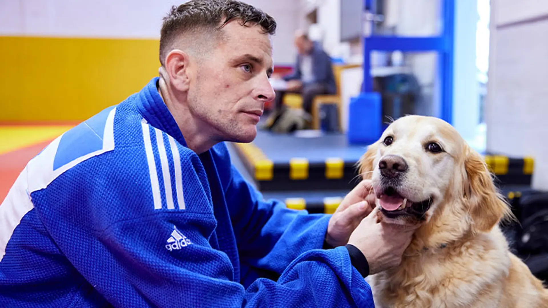 Scott and Milo sit on the floor in a judo gym.