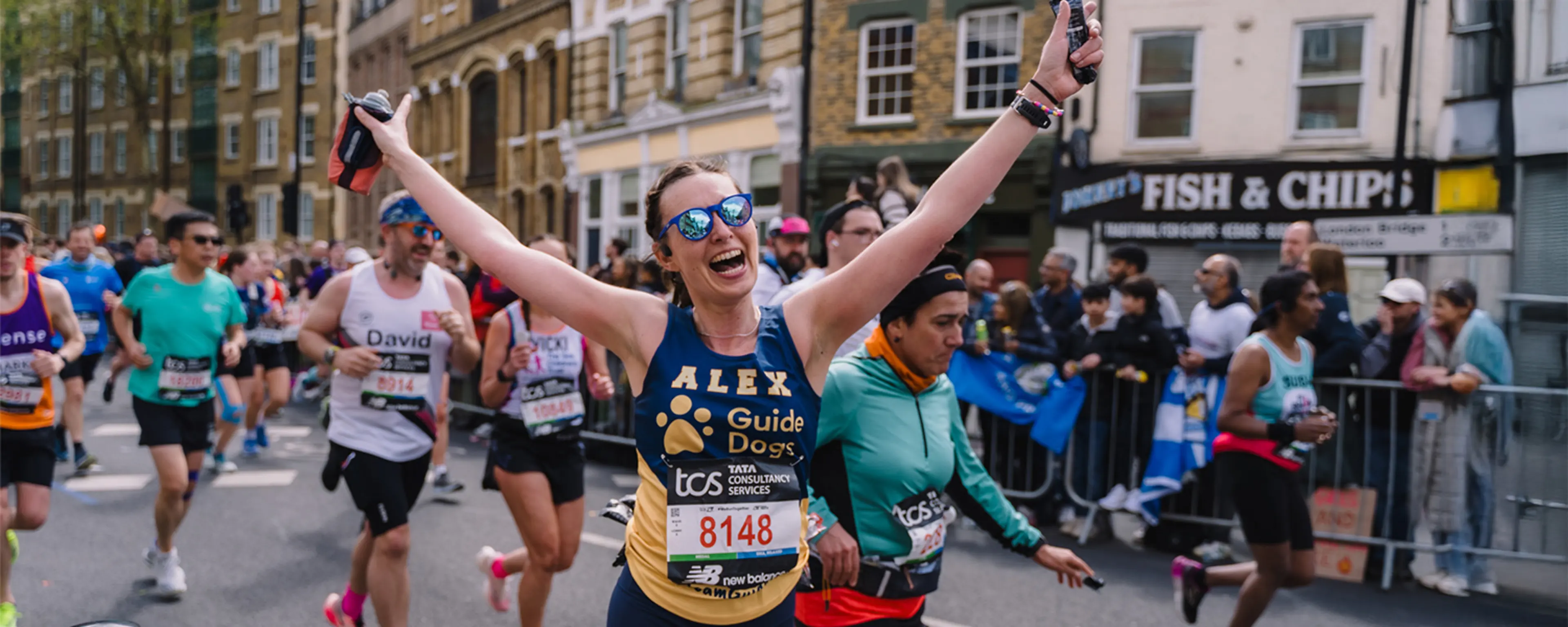 Runner in a Guide Dogs vest at the TCS London Marathon cheering to camera