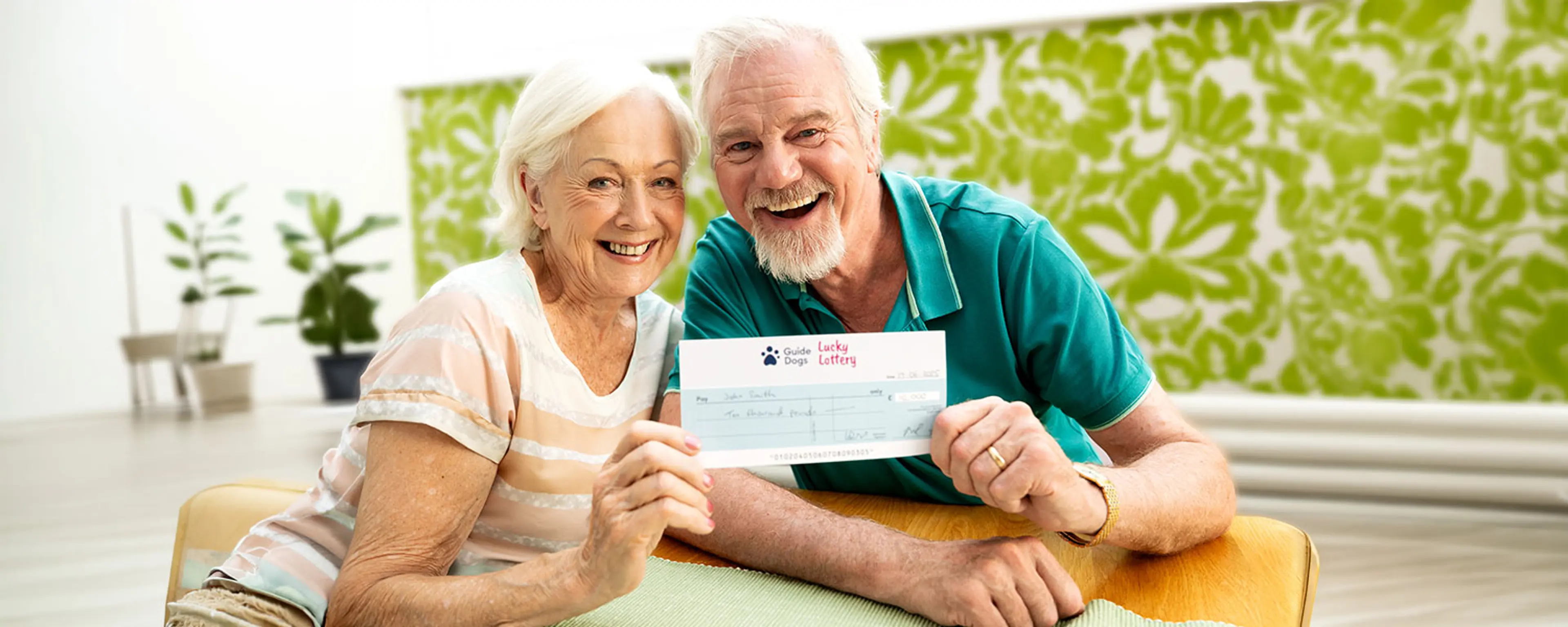 A smiling man and woman holding a cheque between them.