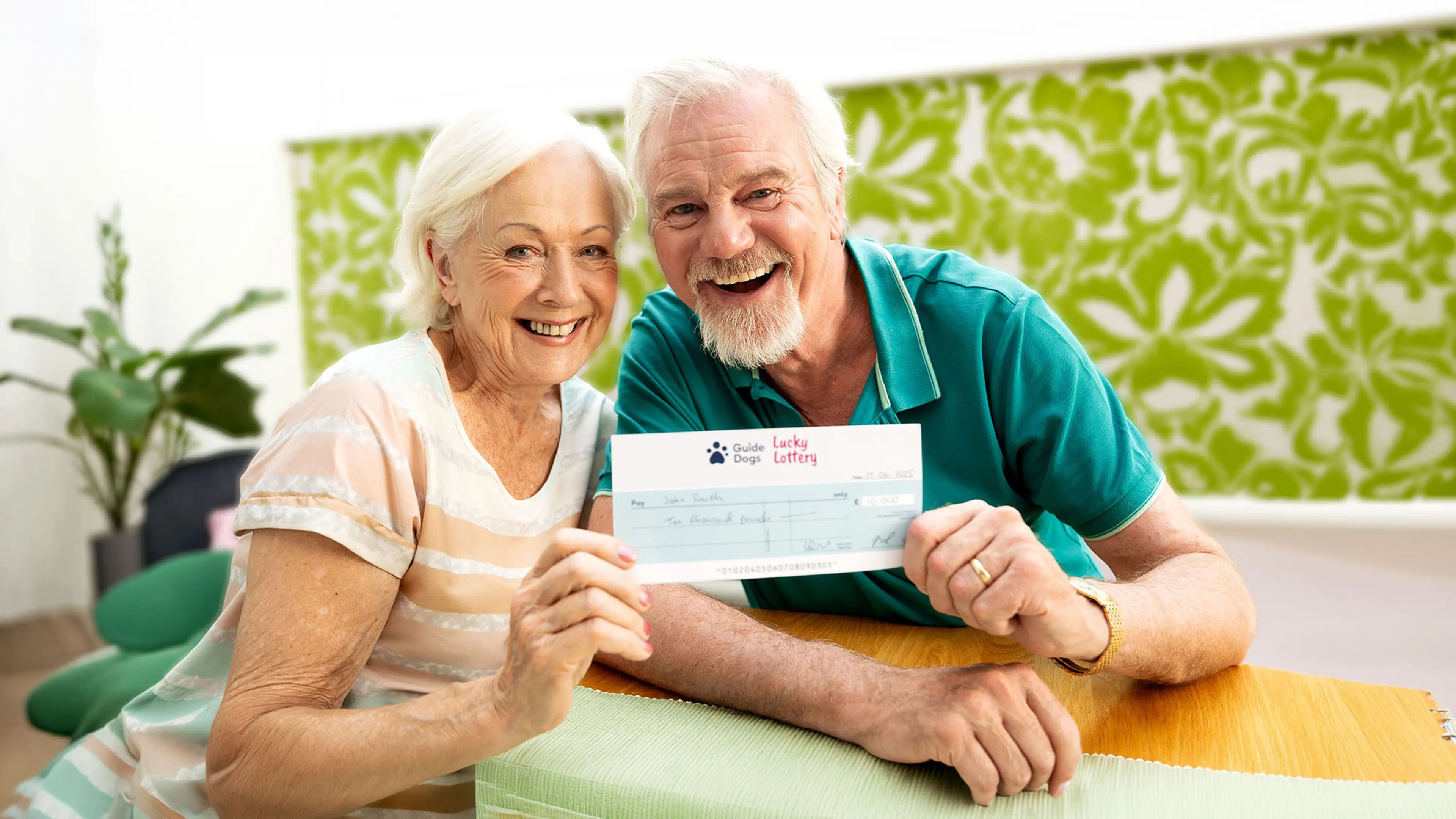 A smiling woman and a man holding a cheque up.
