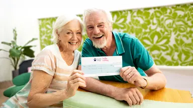 A smiling woman and a man holding a cheque up.