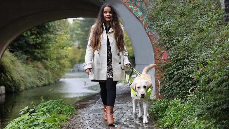 Guide dog owner Hannah and her guide dog Wendy walking along a paved canal path.