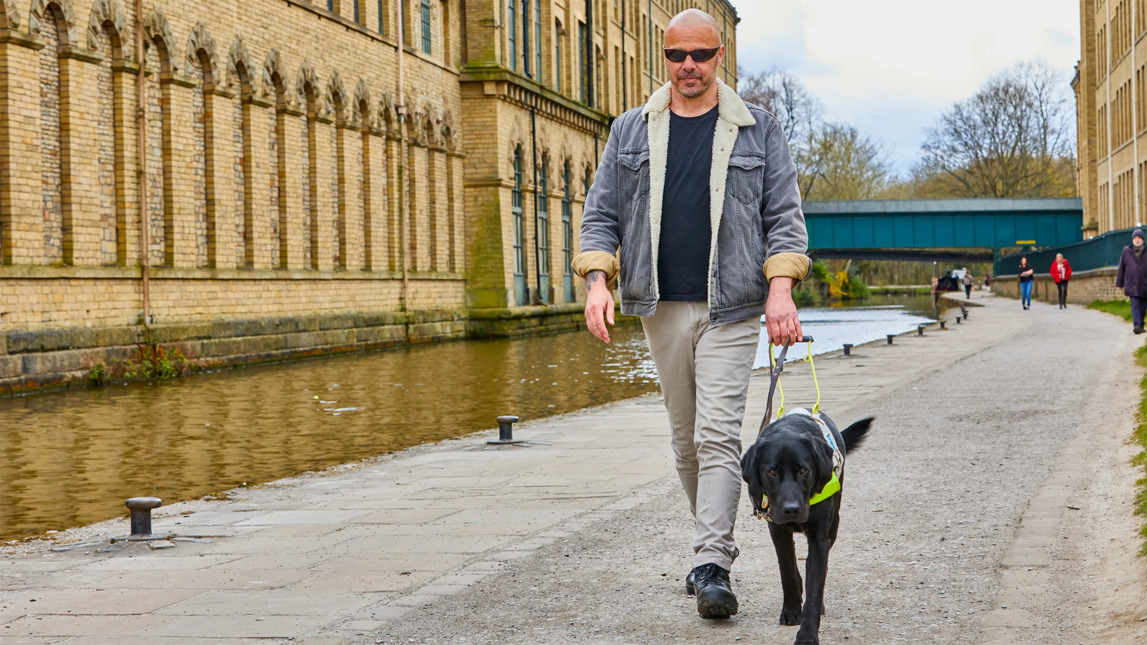 Guide dog owner Terry walks along a canalside path with his guide dog, black Labrador Spencer.