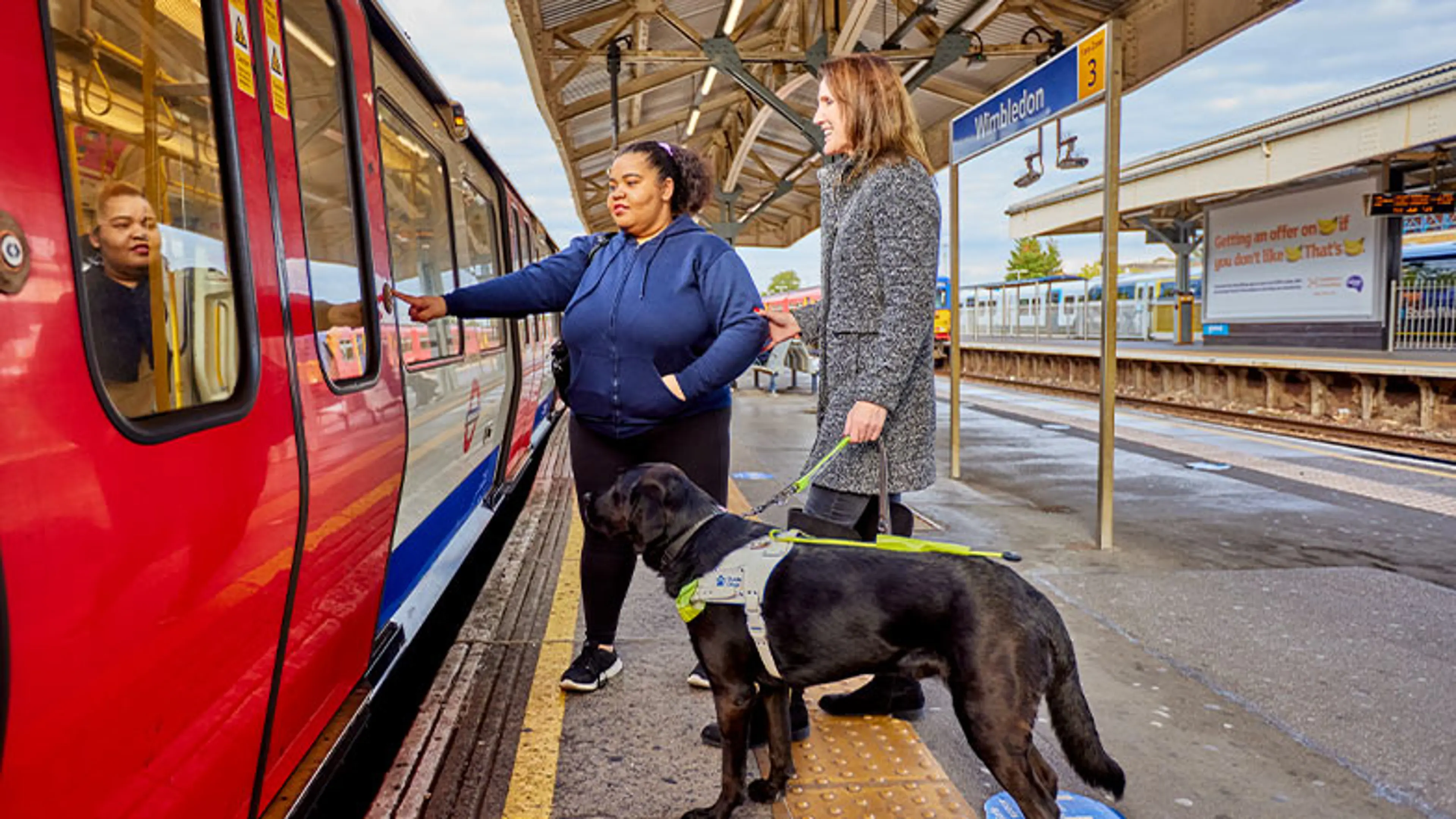 A guide dog owner being guided on a train platform