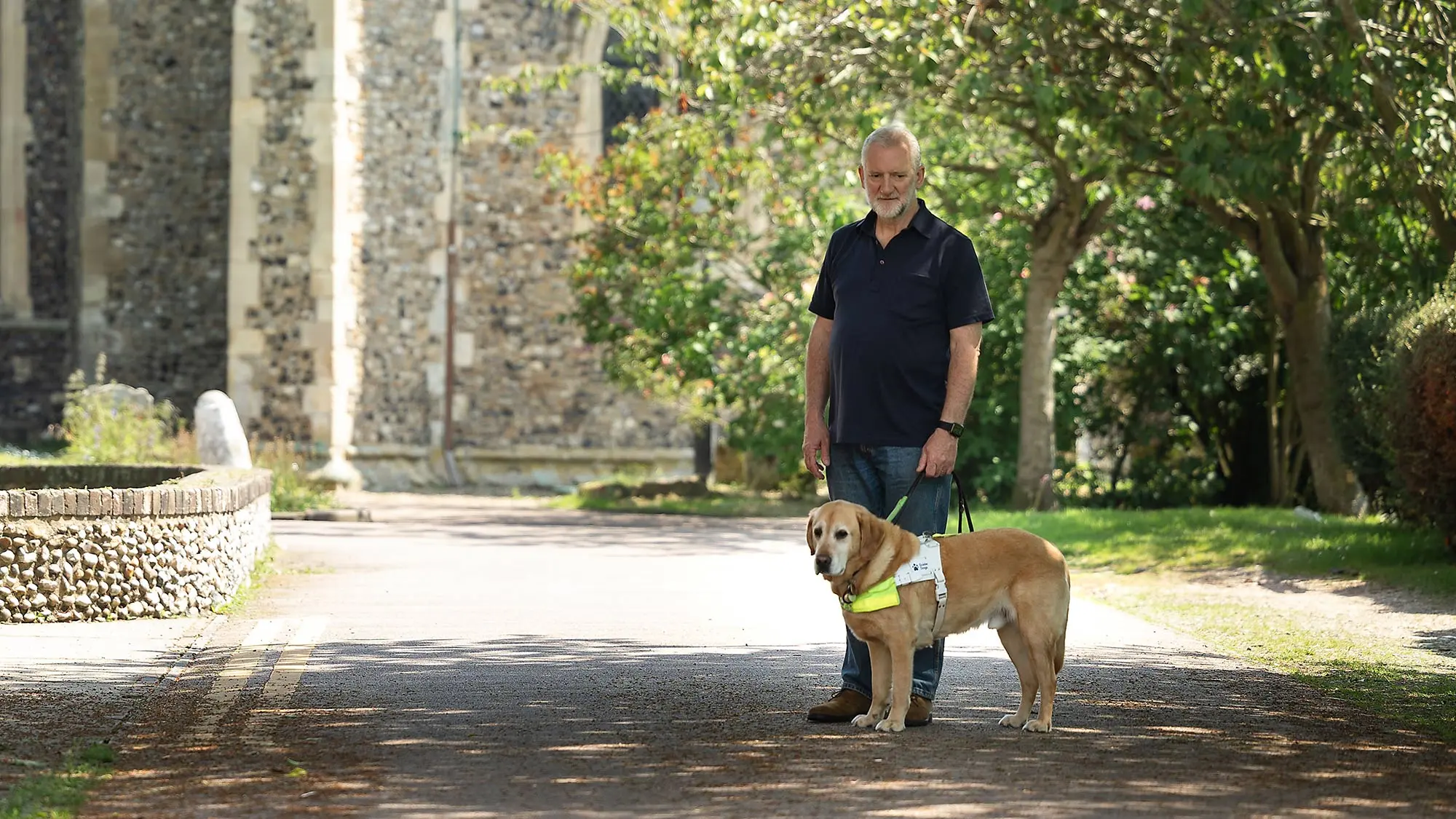 Guide dog owner Simon with his guide dog Mayne outside a church. 