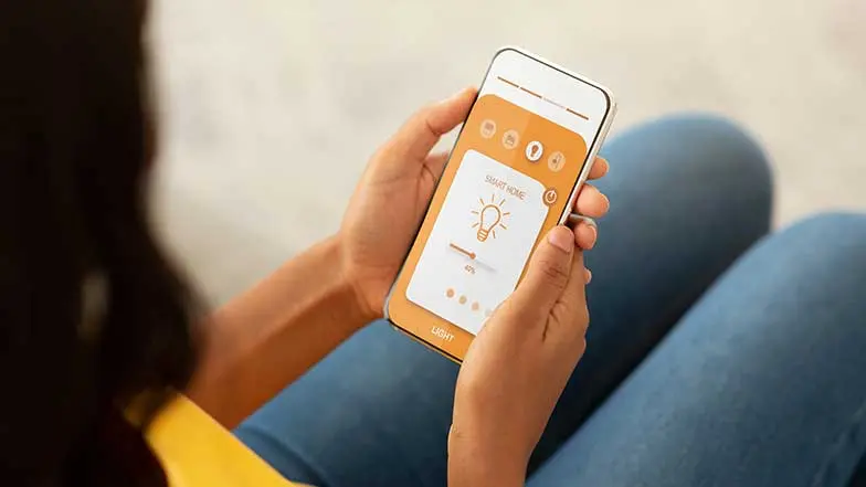 a woman controlling the smart light bulb with her phone