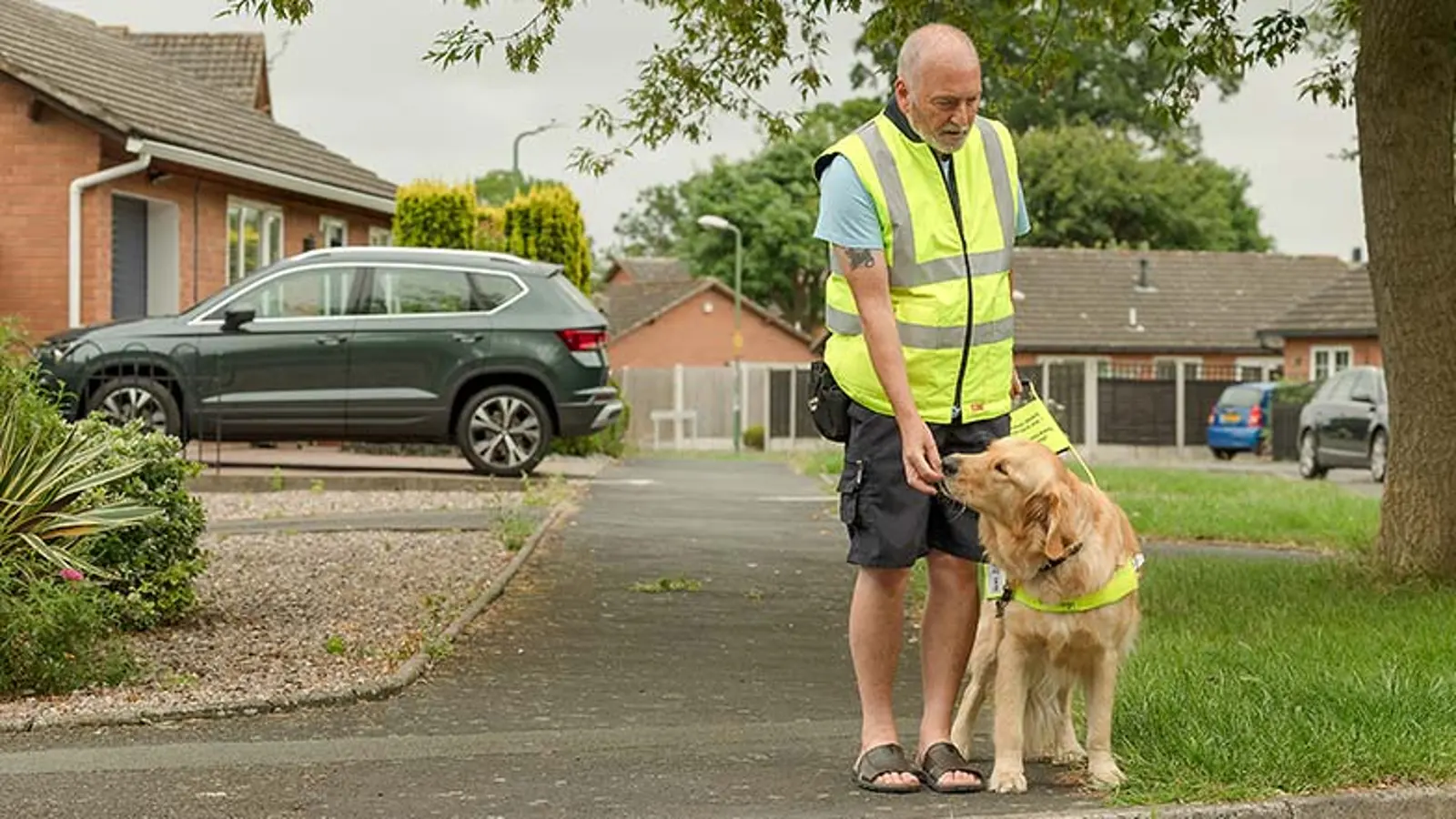 A guide dog owner rewards his guide dog with food as they stop at a kurb