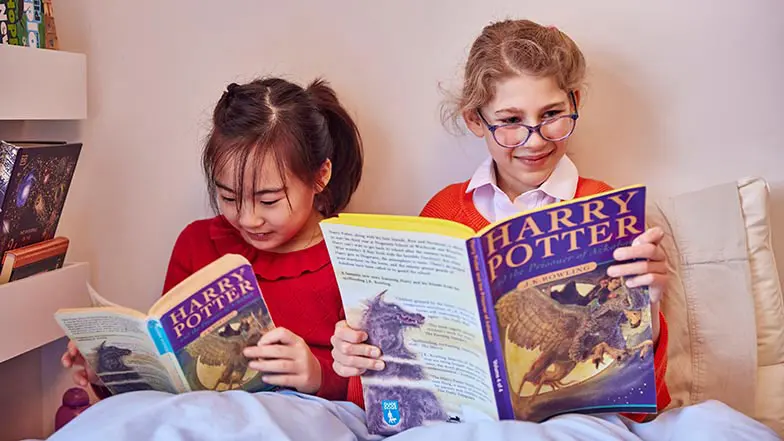 Two school children reading Harry Potter, one is reading a CustomEyes version of the book. 
