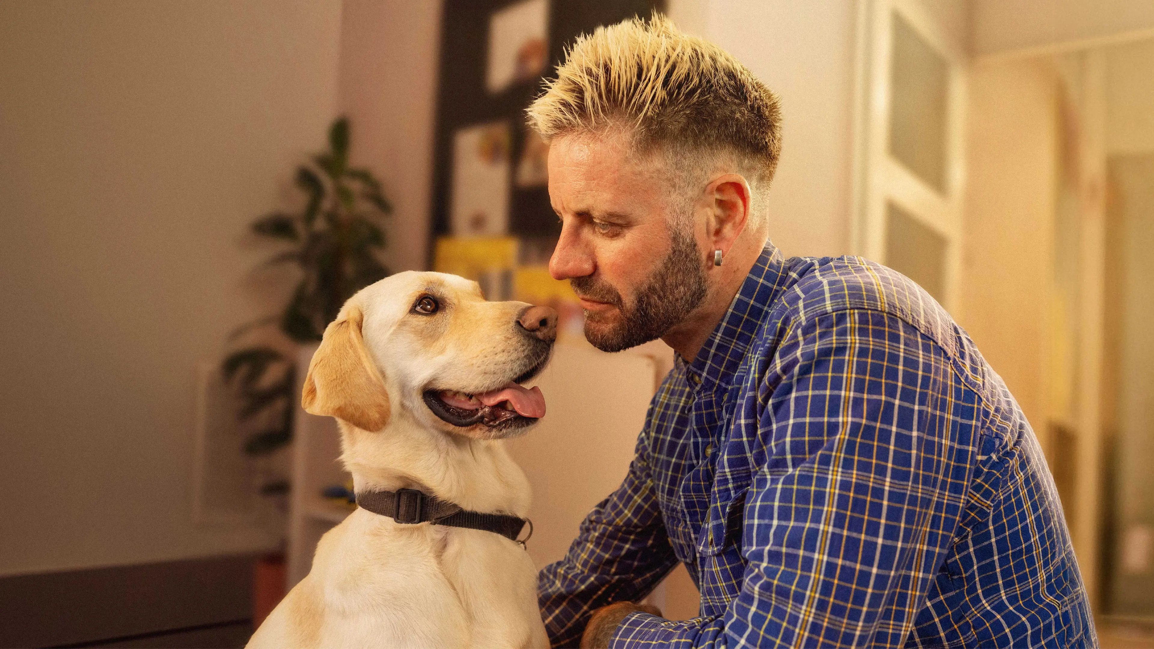 Ross sits beside his guide dog at home. They look at each other affectionately.