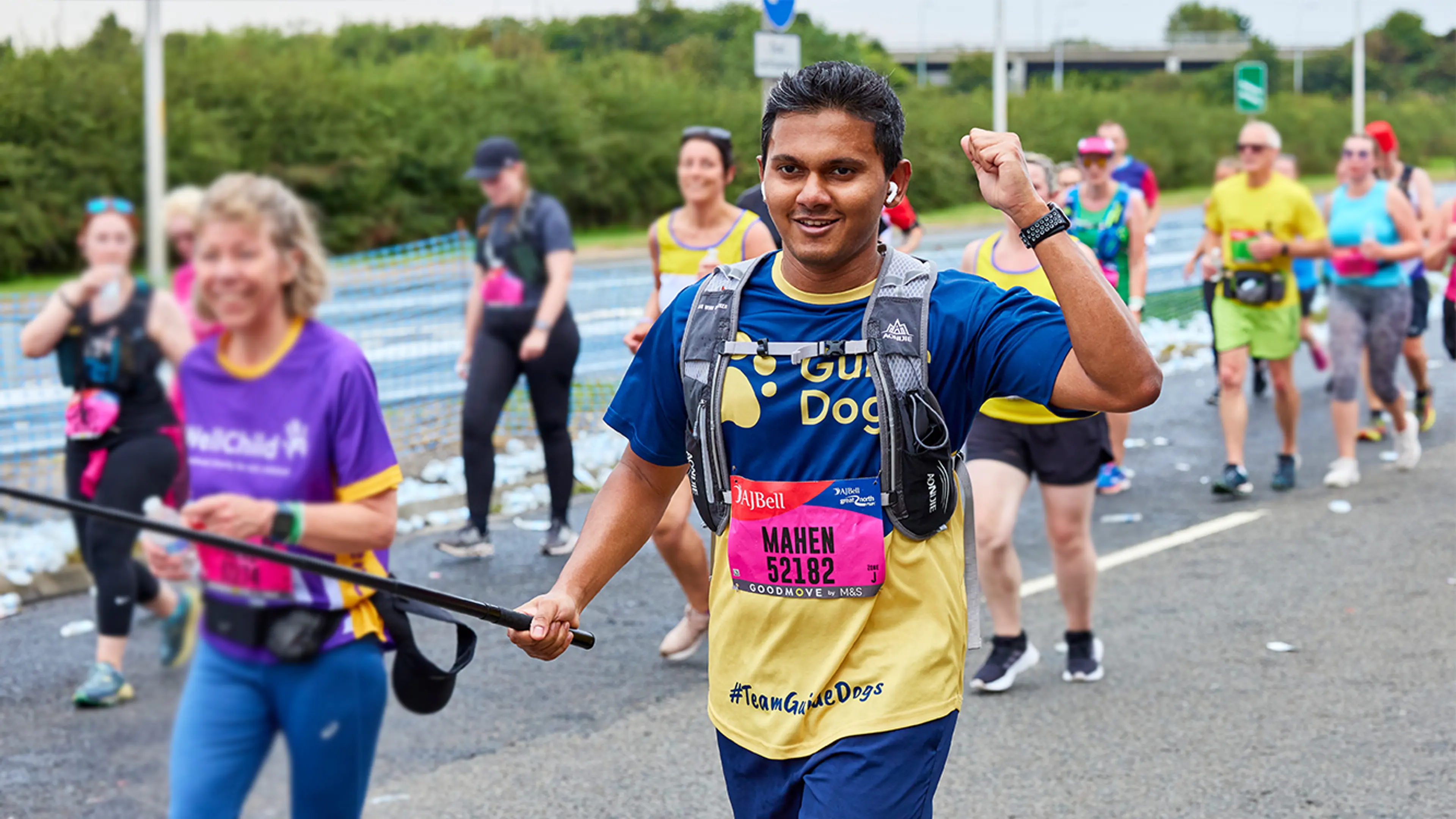 Marathon runner in a Guide Dogs t-shirt running the Great north run Marathon with a happy smile on his face.