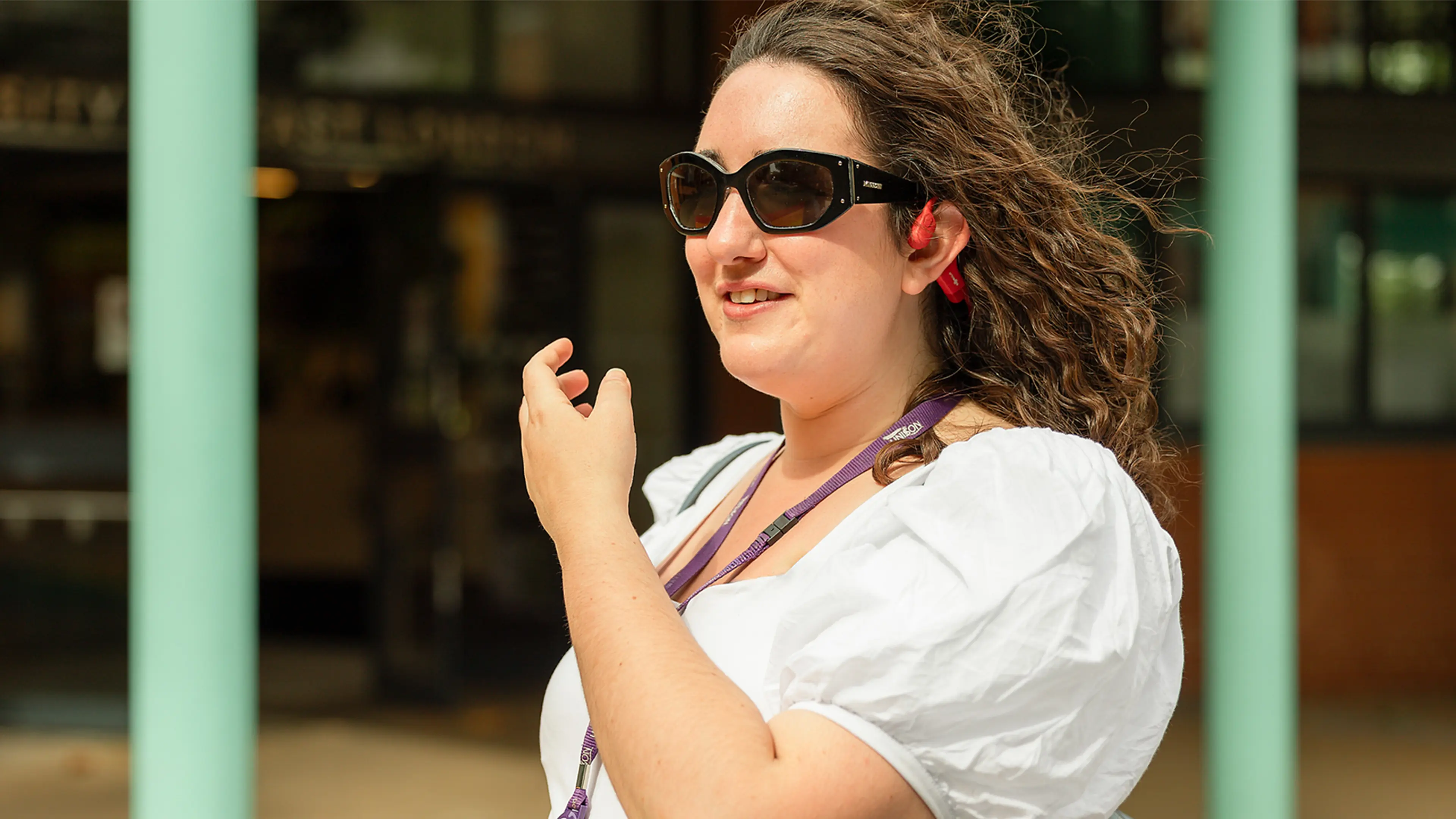 Cerys, who has a vision impairment, demonstrates walking along a pavement using headphones and a cane.