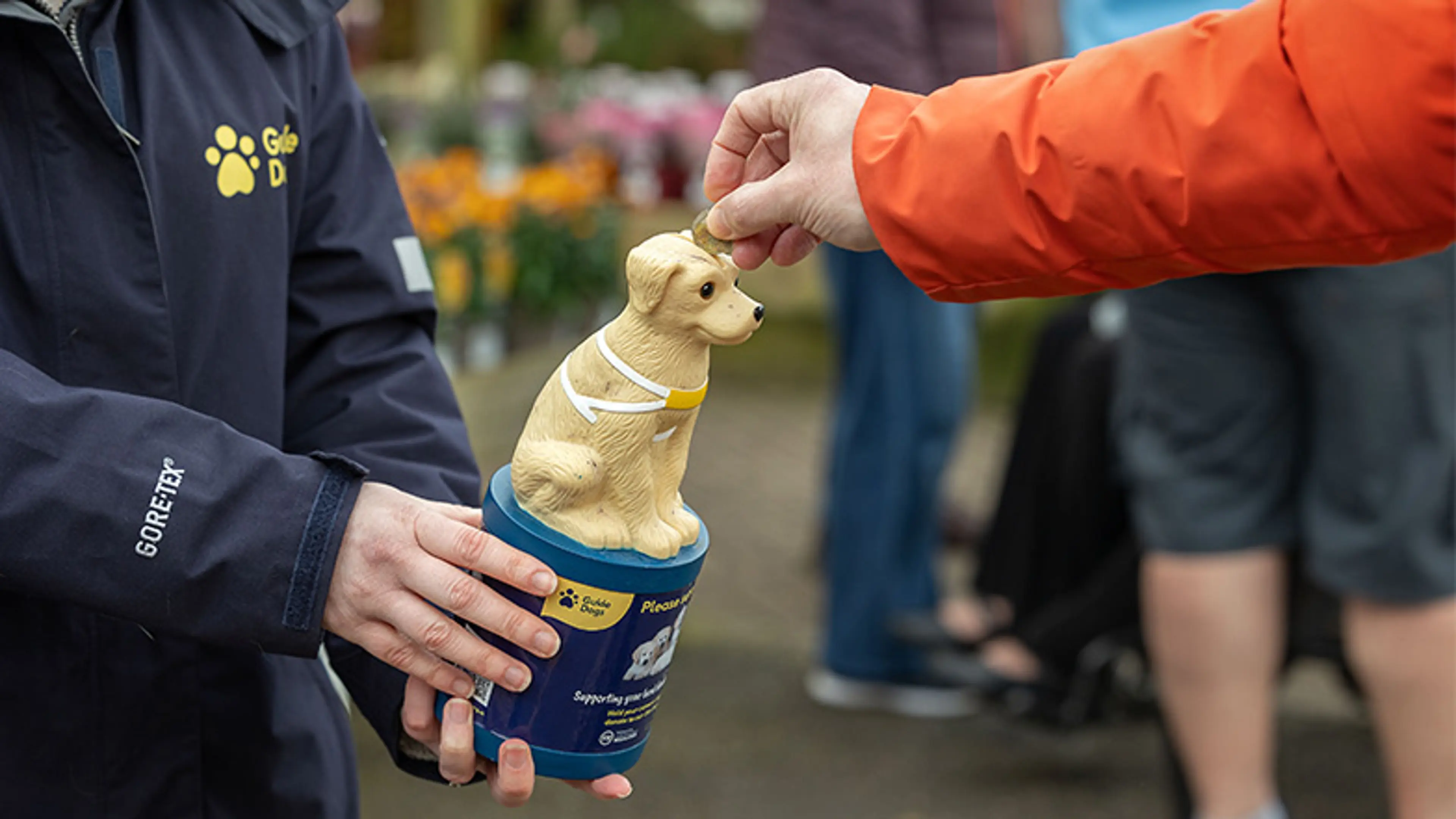 A volunteer holds a collection box whilst someone puts money in