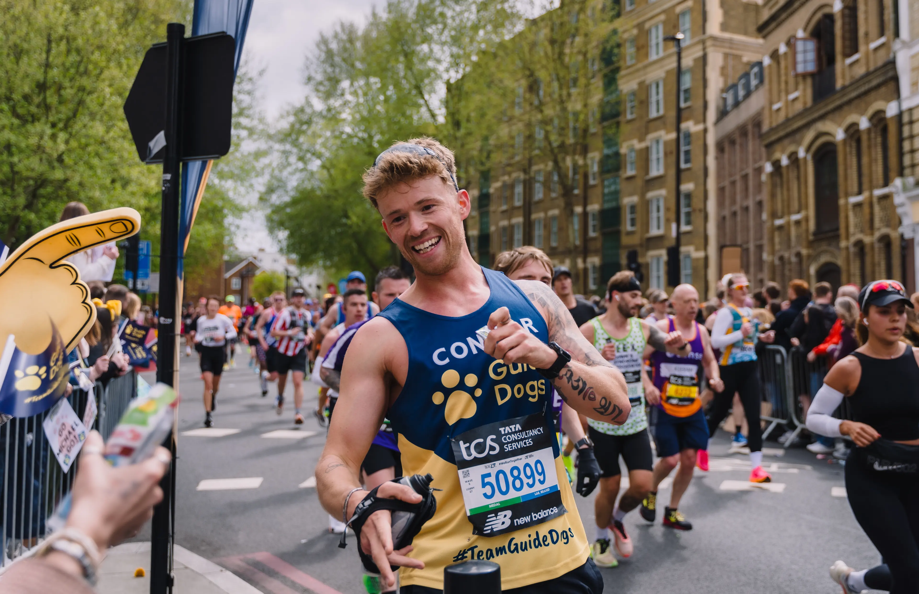 A Guide Dogs London Marathon runner runs past a crowd.