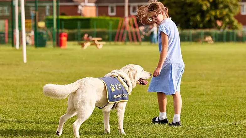 Erin walks alongside her buddy dog in a sunny field.