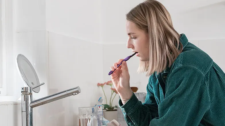 A woman brushing her teeth in front of a mirror