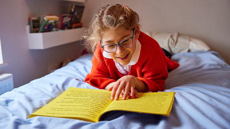 A girl reading a CustomEyes Book on her bed