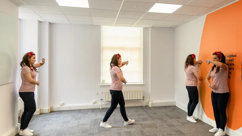 A woman demonstrating the squaring off technique and lower and upper body protection to navigate a new space.