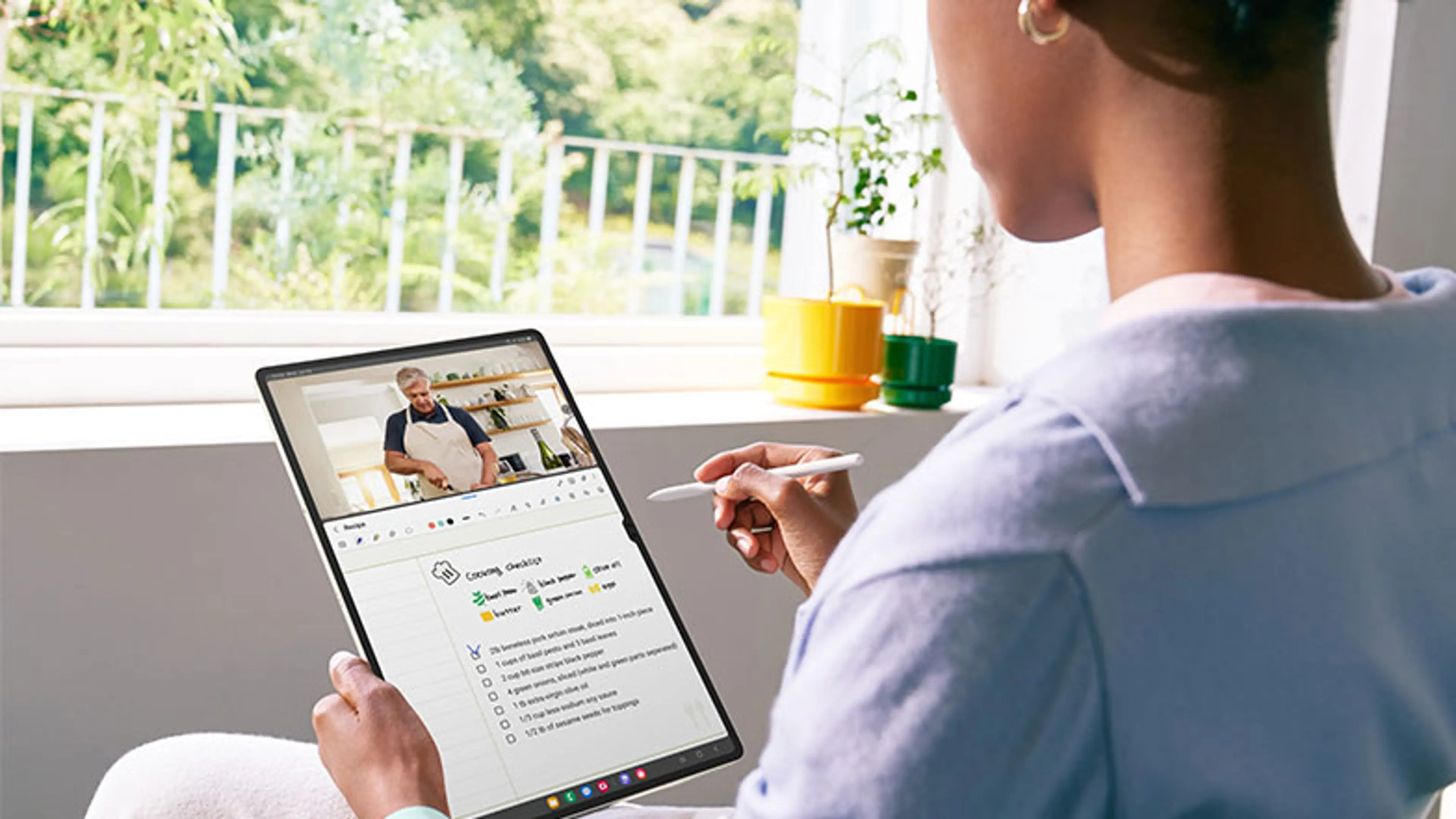 An image of a woman using a Samsung Galaxy Tab S9 with an S-pen stylus