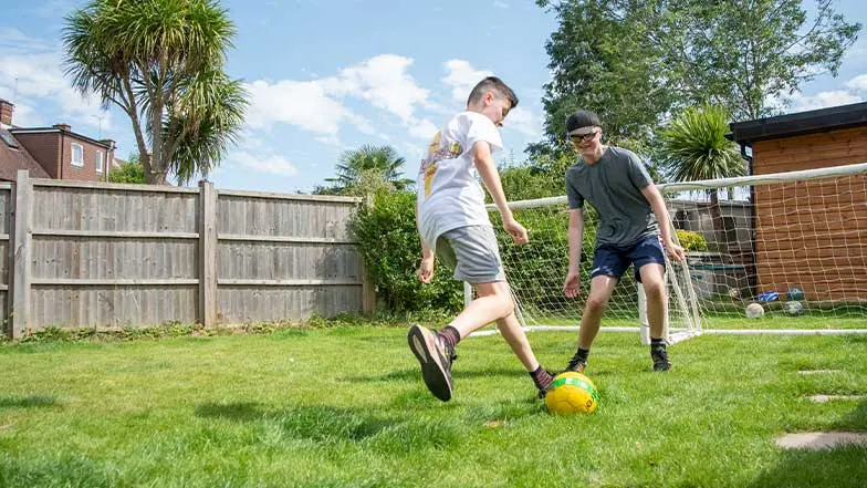 Declan, young service user, and his brother, play football in their garden.
