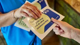 Open Doors for guide dogs and all other assistance dogs sticker being handed from one person to another.