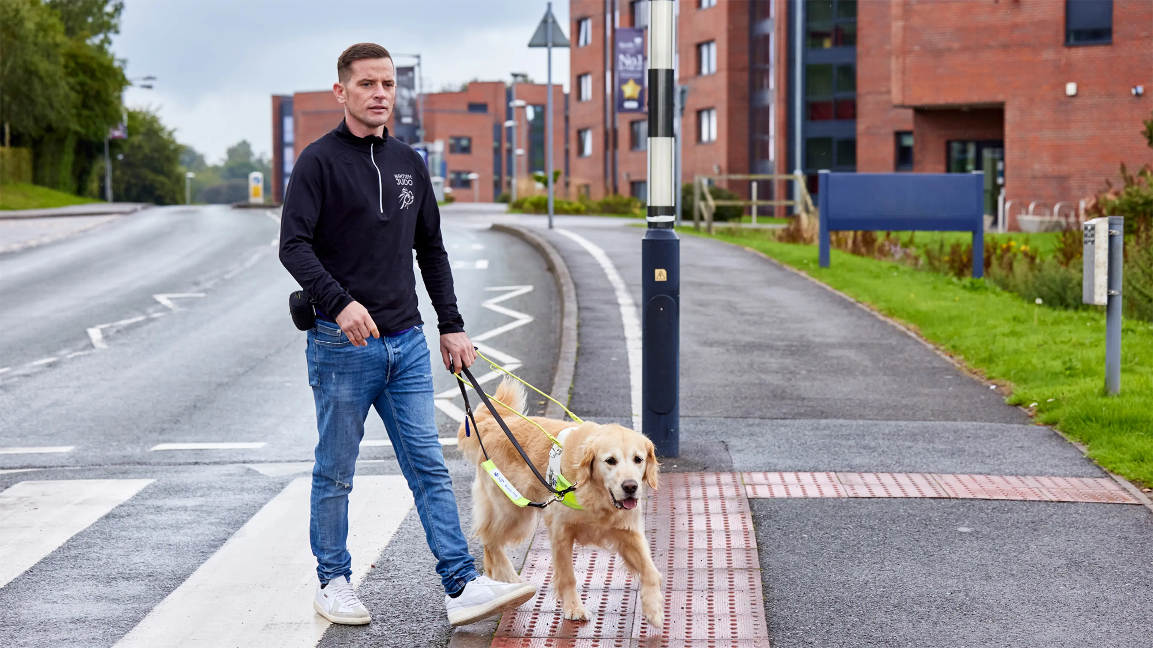 Guide dog owner Scott and his golden retriever guide dog Milo reach the other side of a zebra crossing. 