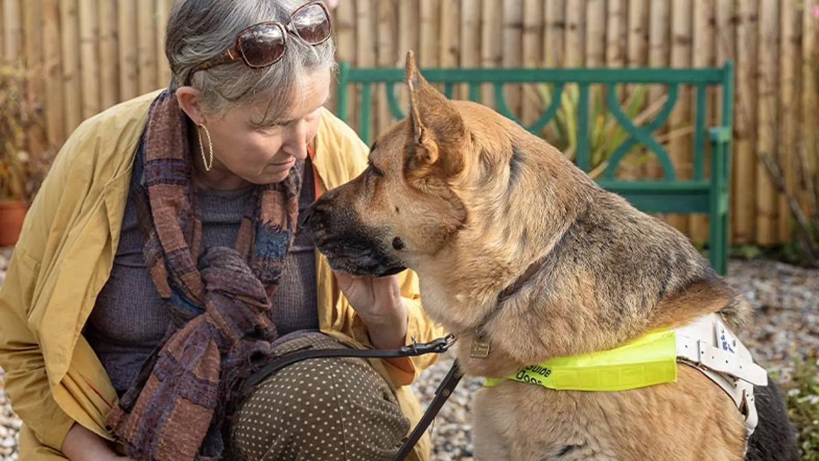 A guide dog owner and her guide dog are sat down while looking at each other.