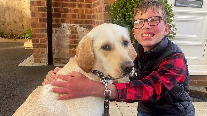 A young boy smiles as he sits with buddy dog.