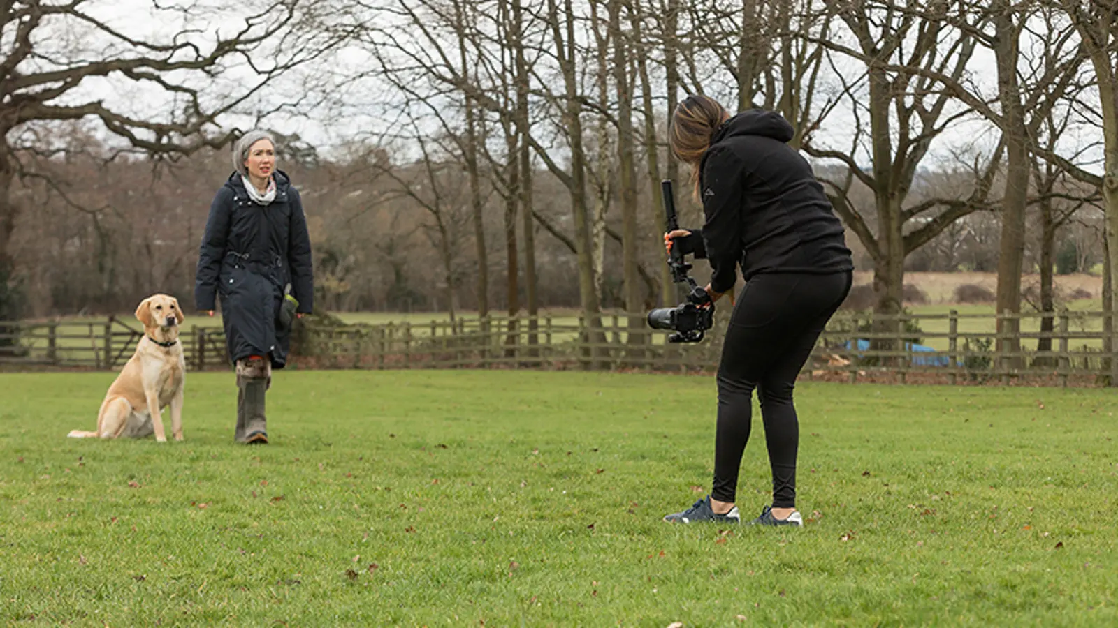 A Video Producer filming a rehomer and her dog in their garden.