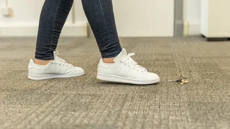 A person searching a small area with their foot for some dropped keys.