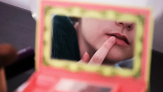 A woman applying lipstick with her finger