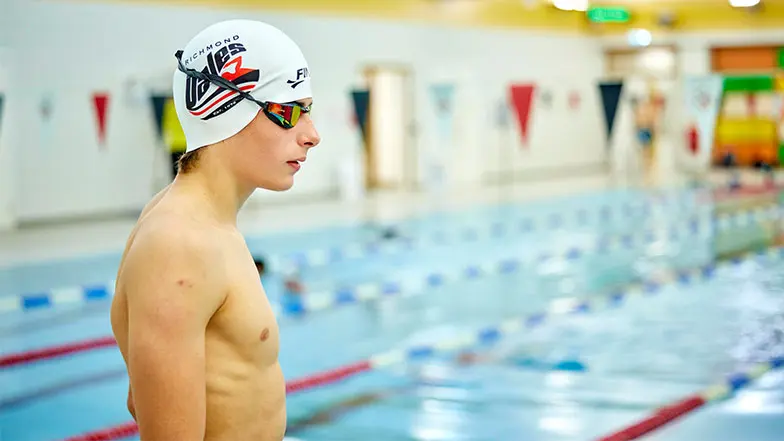 Archie standing outside a swimming pool ready to dive in