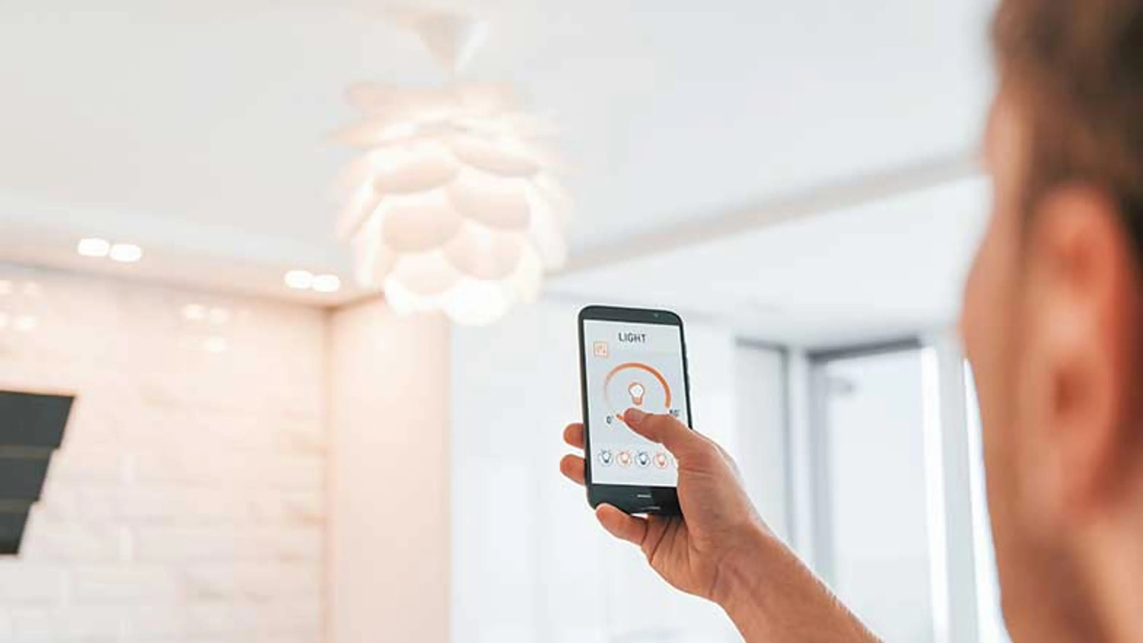 A man operating a smart lightbulb from his phone. 