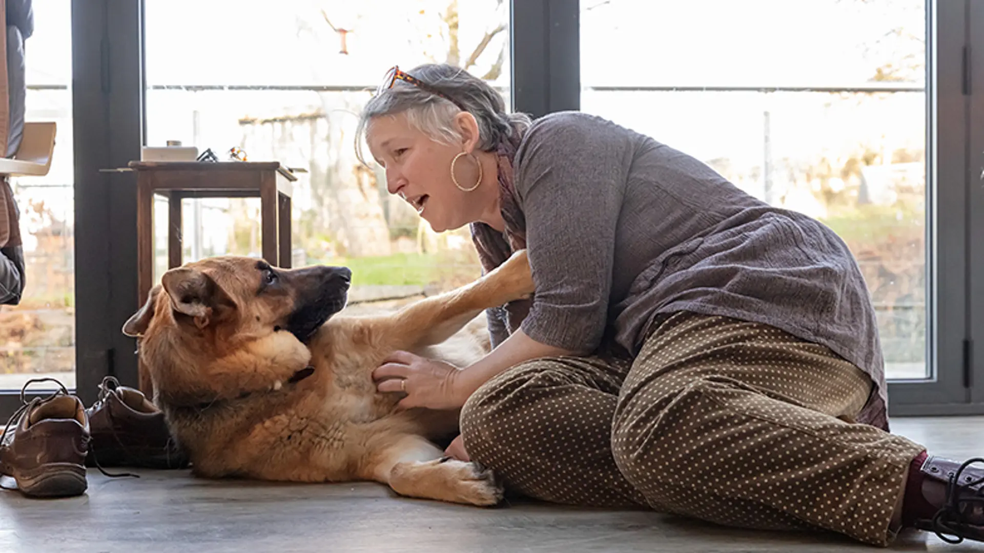 A guide dog owner sitting on the floor with her guide dog.