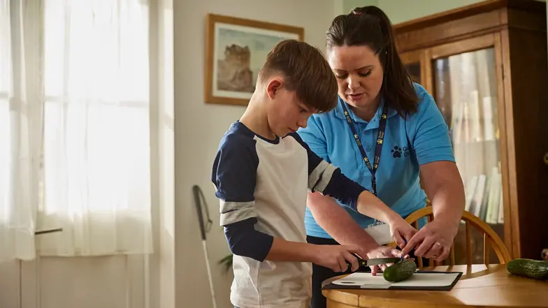 A young service user is learning kitchen skills guided by his Habilitation Specialist