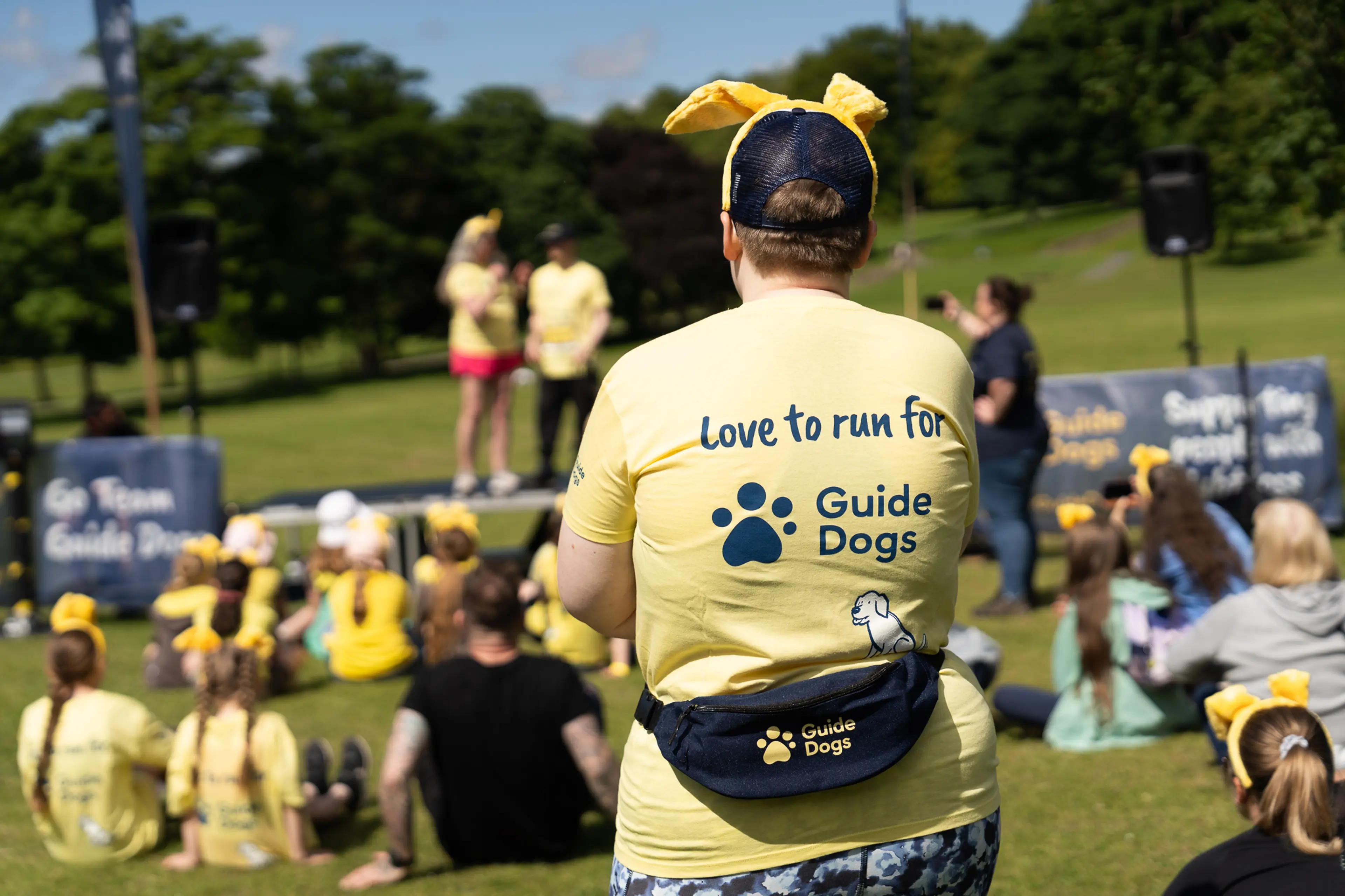 Person in Guide Dogs t-shirt saying 'love to run for Guide Dogs' and wearing dog ears.