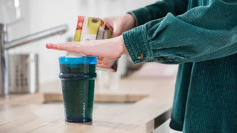 A person pouring juice into a glass using a ball to indicate liquid level