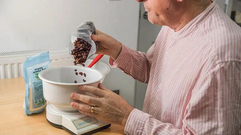 Image of a man pouring some rains into a set of talking scales