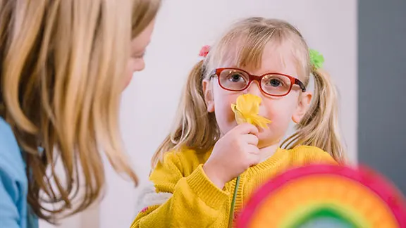 Alma, with her Guide Dogs mobility training instructor, smelling a daffodil