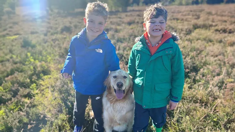 Alex and Chance stand alongside Alex's brother outside. They're all smiling.